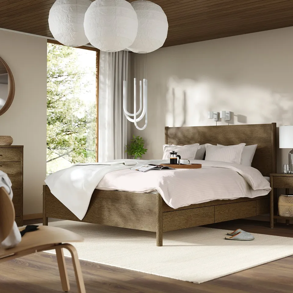 Modern bedroom with TONSTAD bed, soft-close drawers, large windows, pendant lamp, wooden nightstands, white rug, peach chair, small mirror.