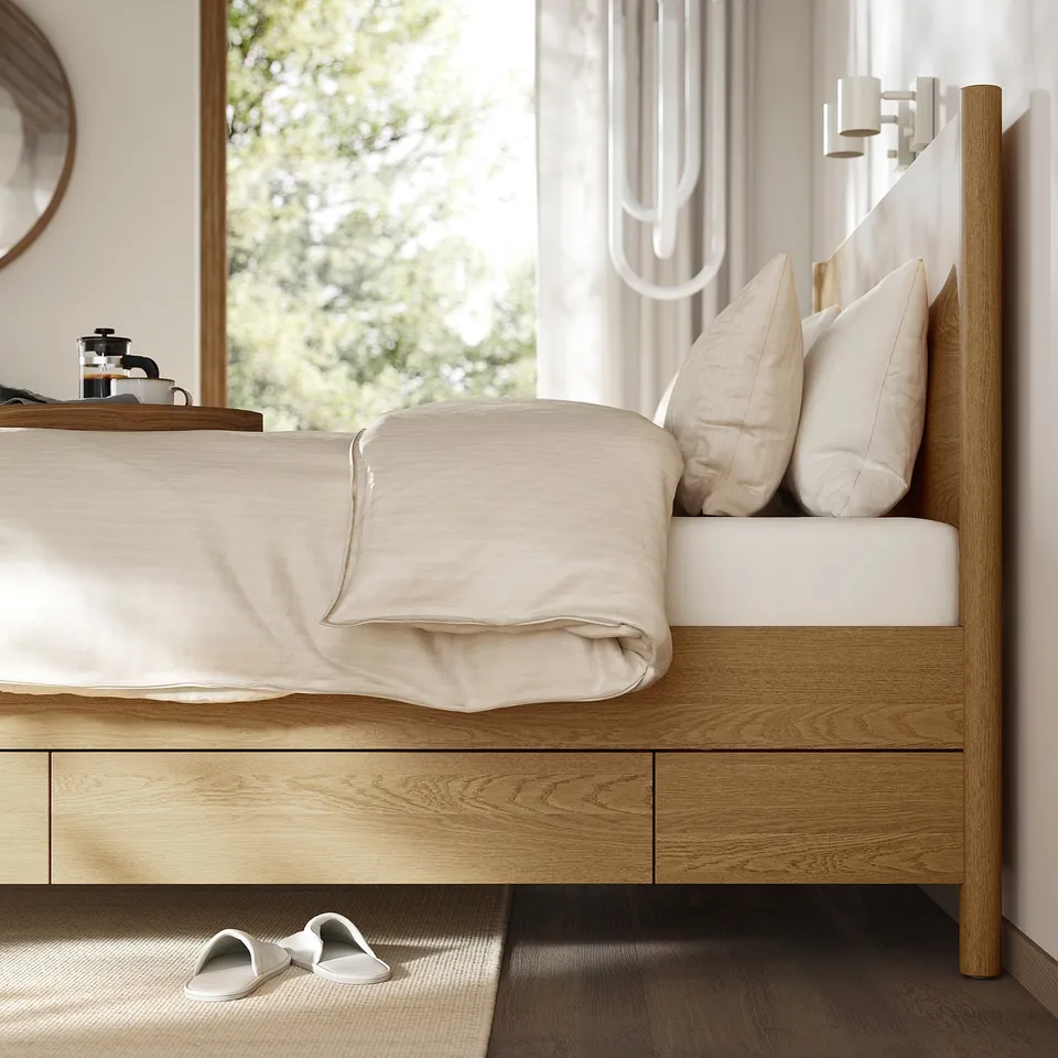 Bedroom scene with TONSTAD bed, featuring soft-close drawers and slatted base. White blankets, pillows, and slippers are nearby.