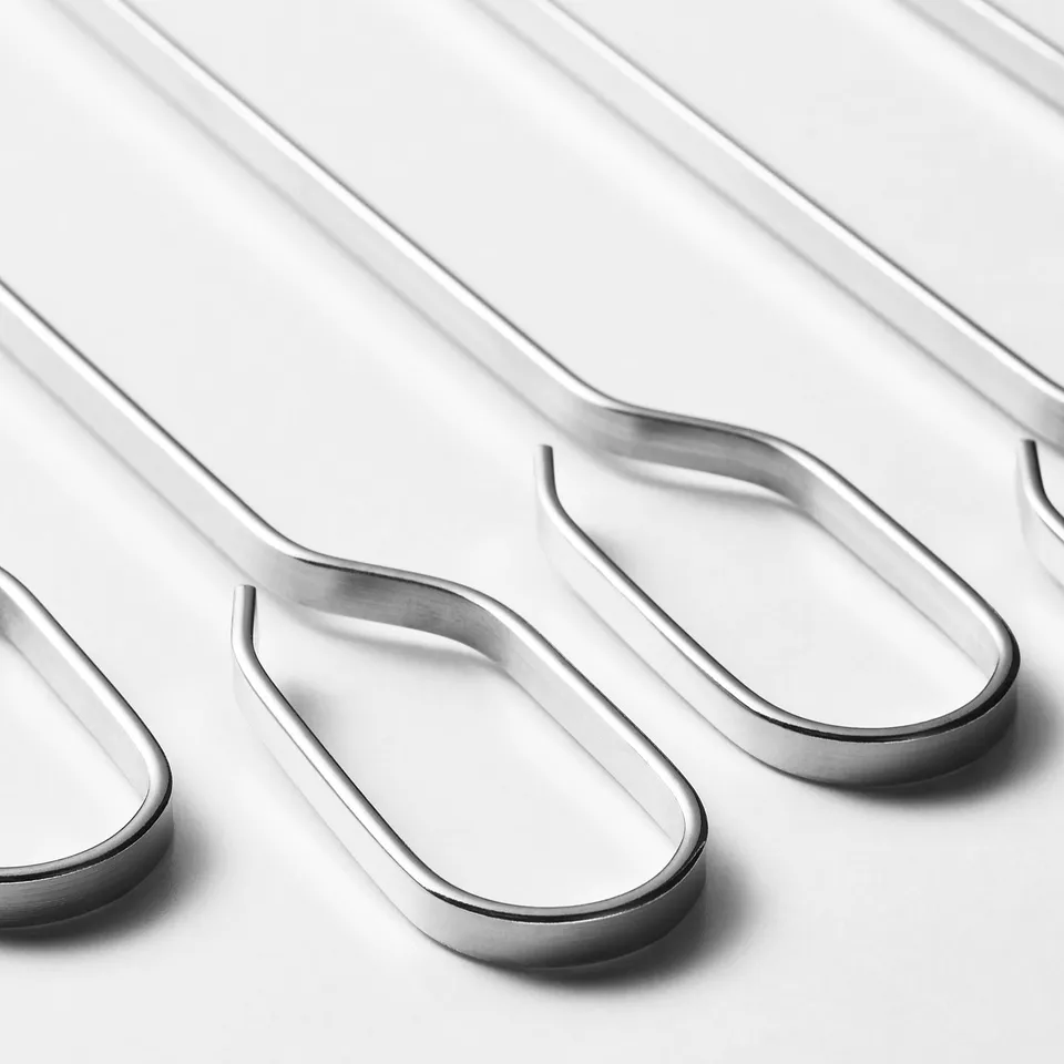 Multiple metal grilling skewers laid out neatly, shiny and well-crafted, ready for use.