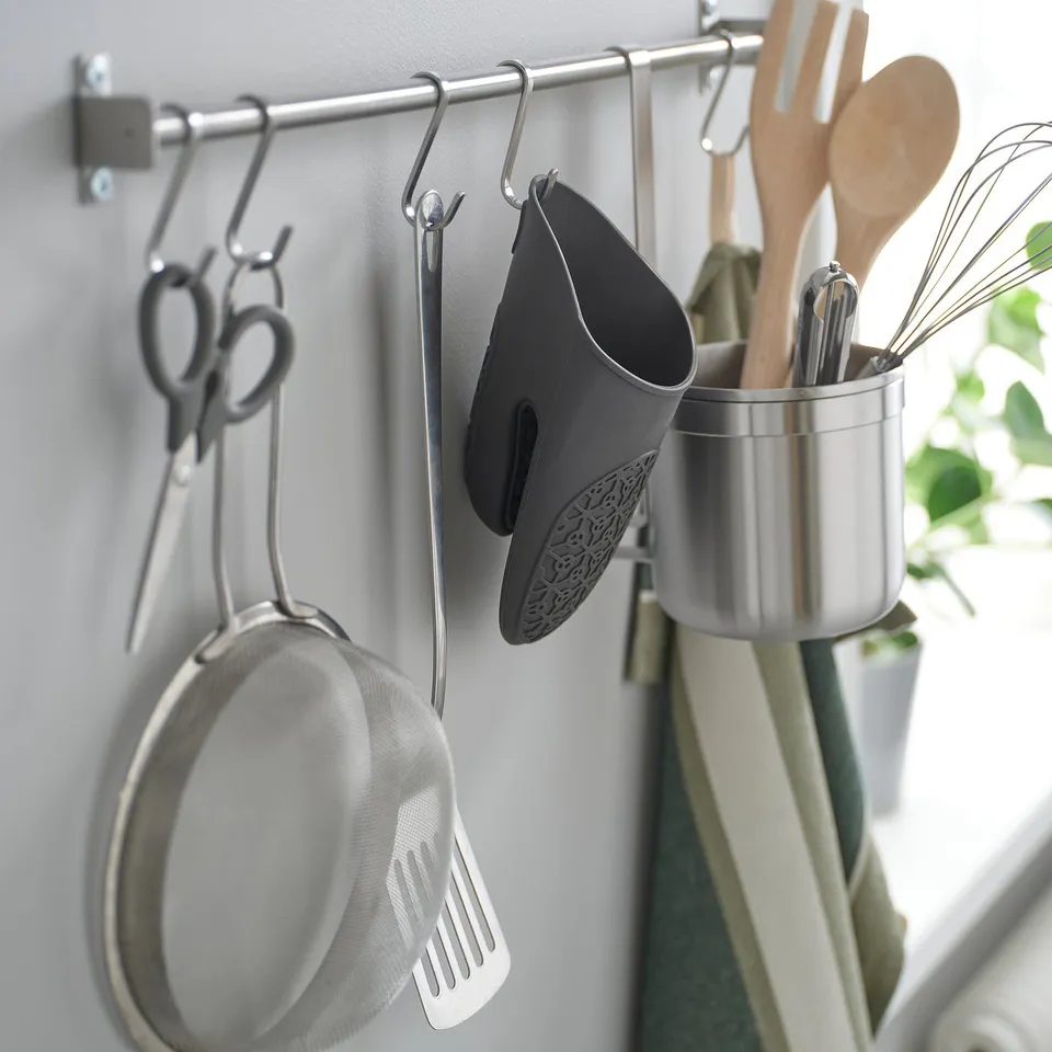 Kitchen hooks holding tools: sieve, spatula, oven mitt, scissors, and utensils.