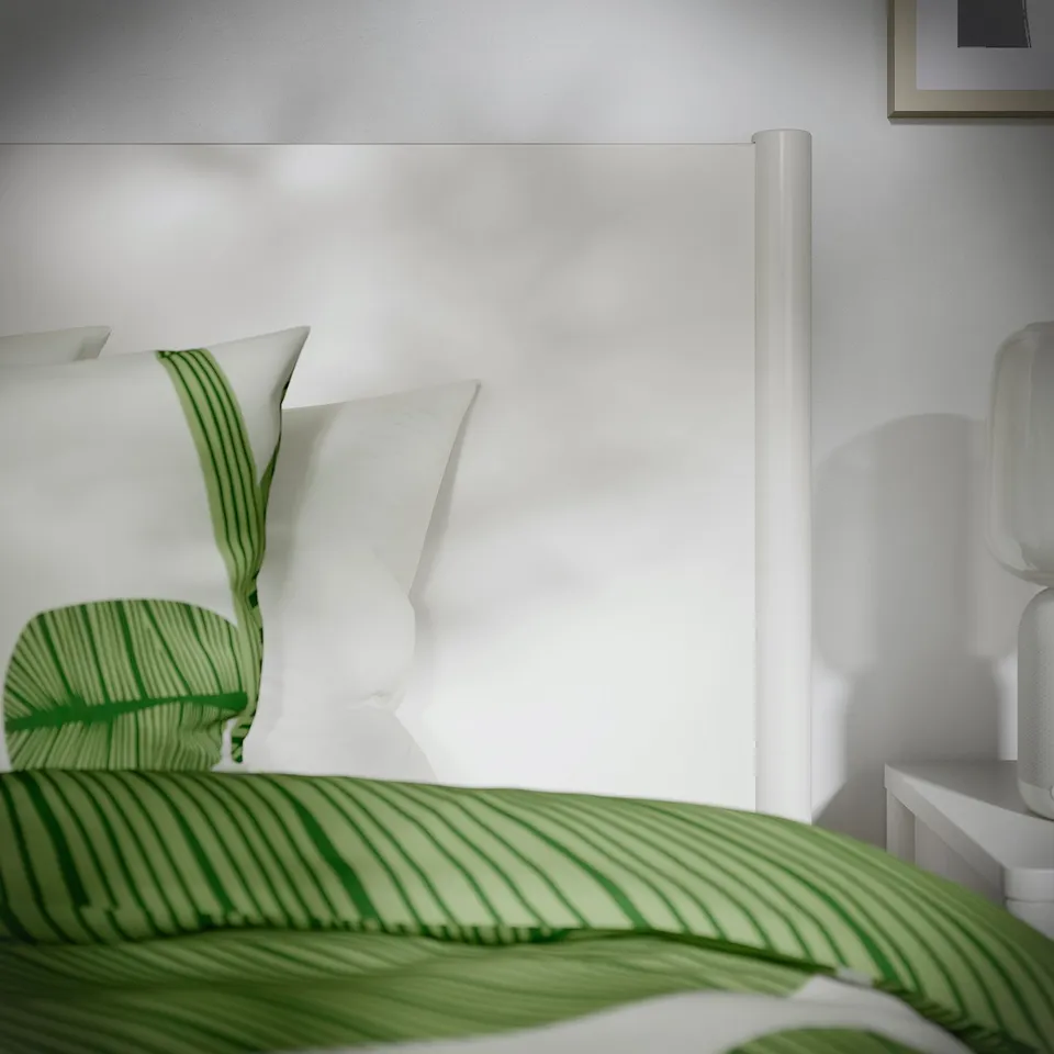Modern white bed with green striped sheets, showcasing quality design and texture.