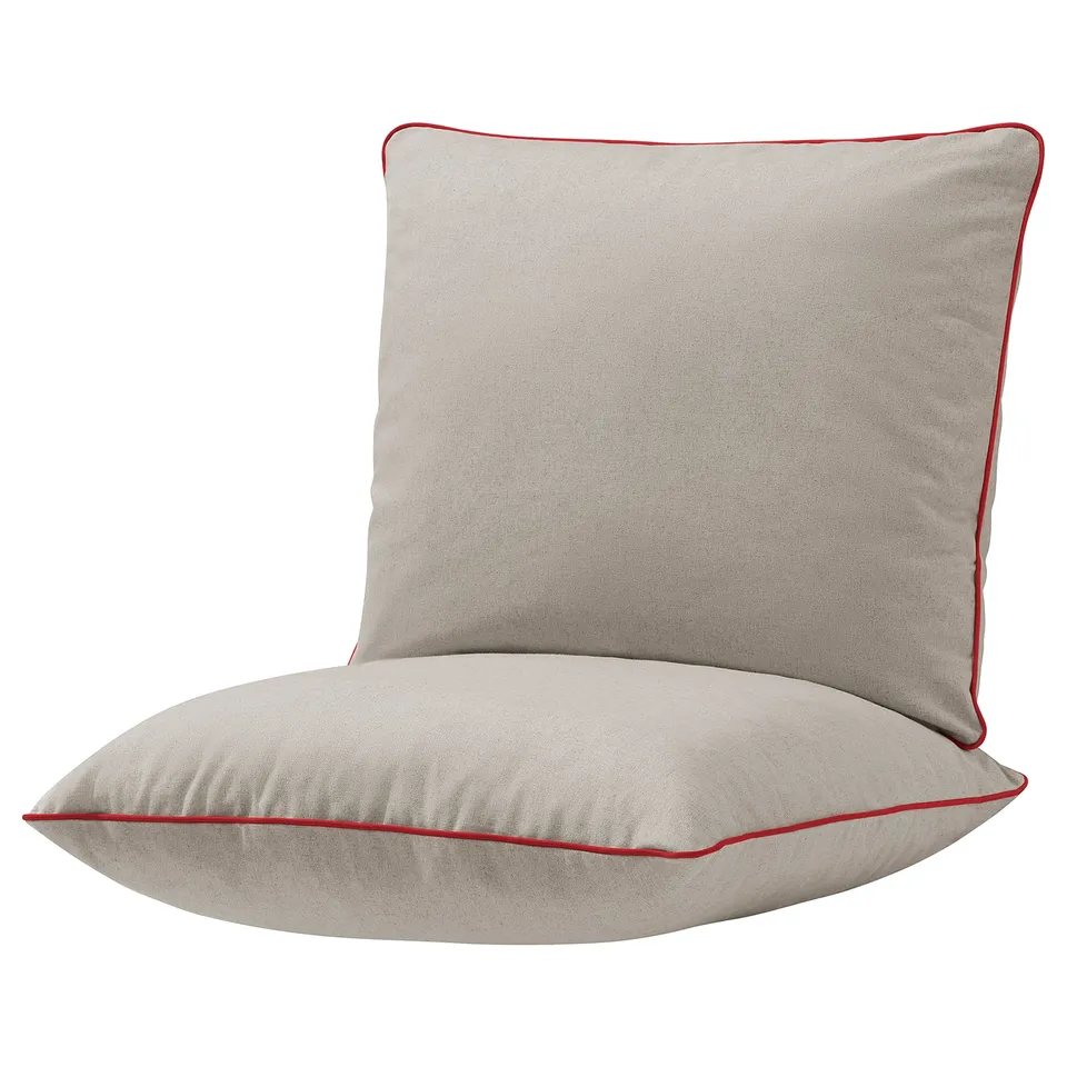 An beige outdoor cushion set with red piping. It is square-shaped and designed for comfort, fitting an armchair frame.