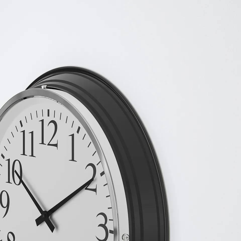 Silent clock close-up. Modern design, black frame, white face, and large black numbers and hands. Steel and glass.