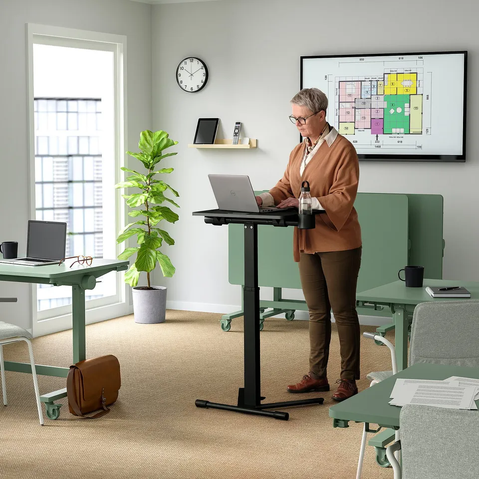 Person uses height-adjustable laptop table in modern office. Ideal for presentations or temporary work.