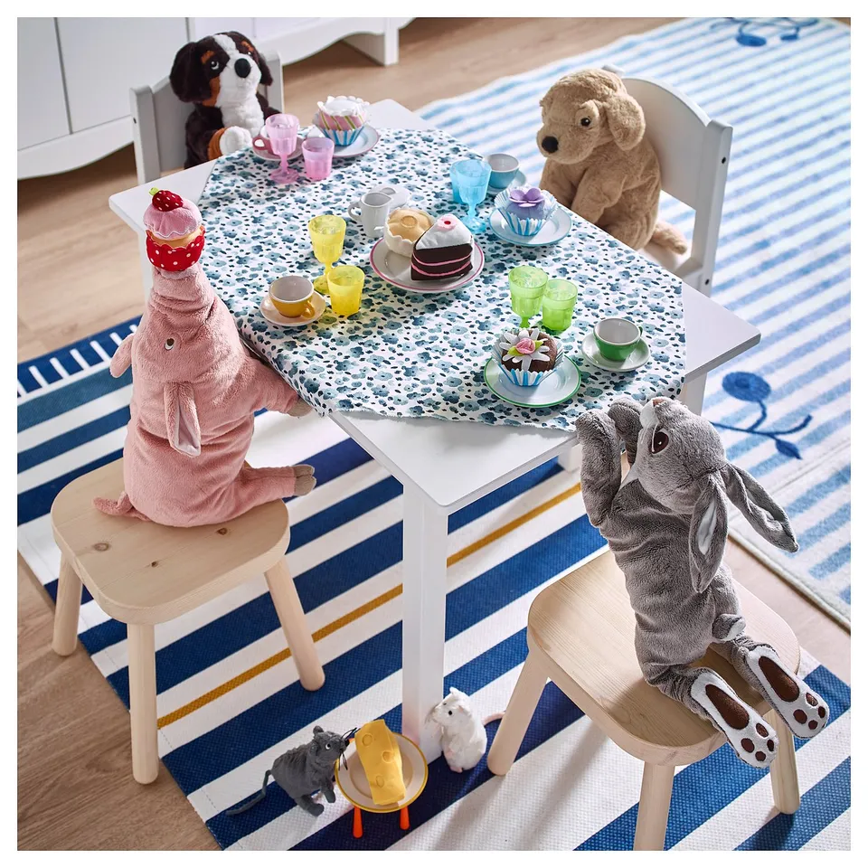 Playful table setting with stuffed animals seated around a colourful table. Toys, plates, cups, and treats in a fun environment.