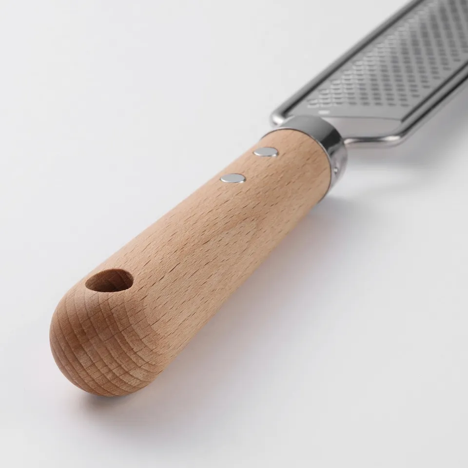 A stainless steel grater with a robust, oiled beechwood handle featuring a hanging hole, designed for efficient food zesting or grating.