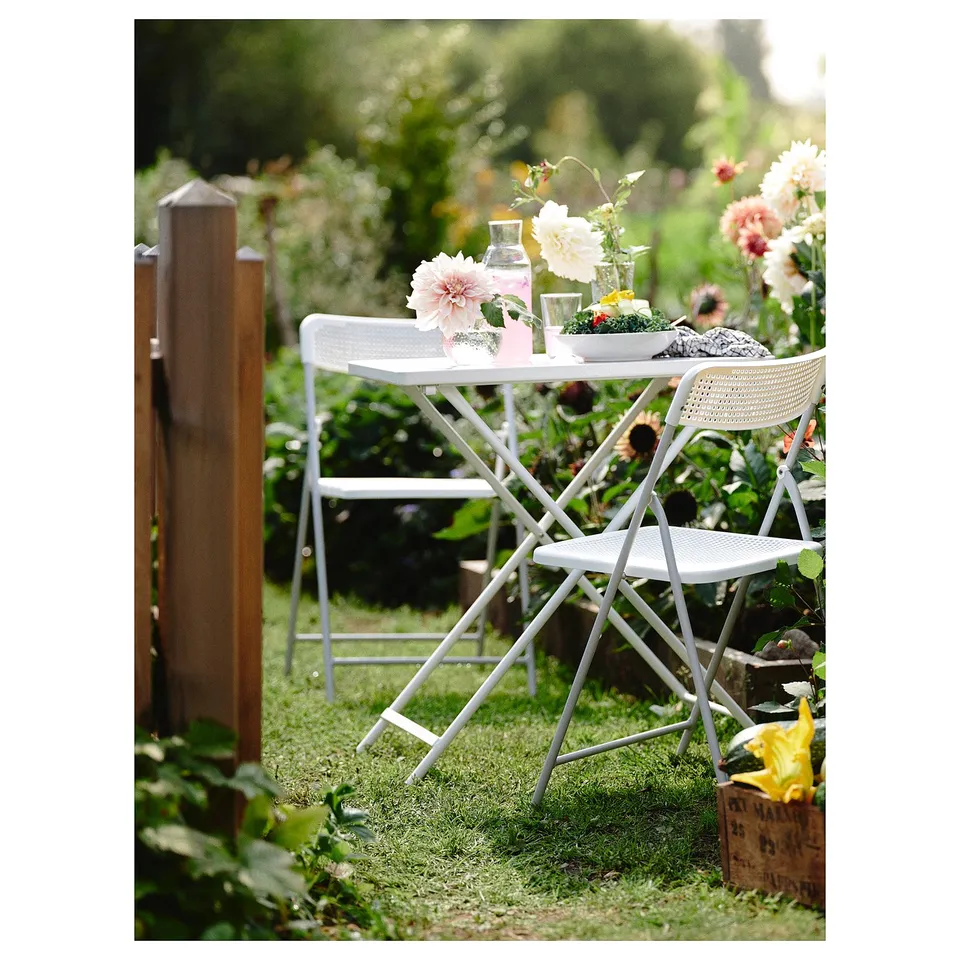 White TORPARÖ outdoor dining set with table, two chairs, vase, and glasses.