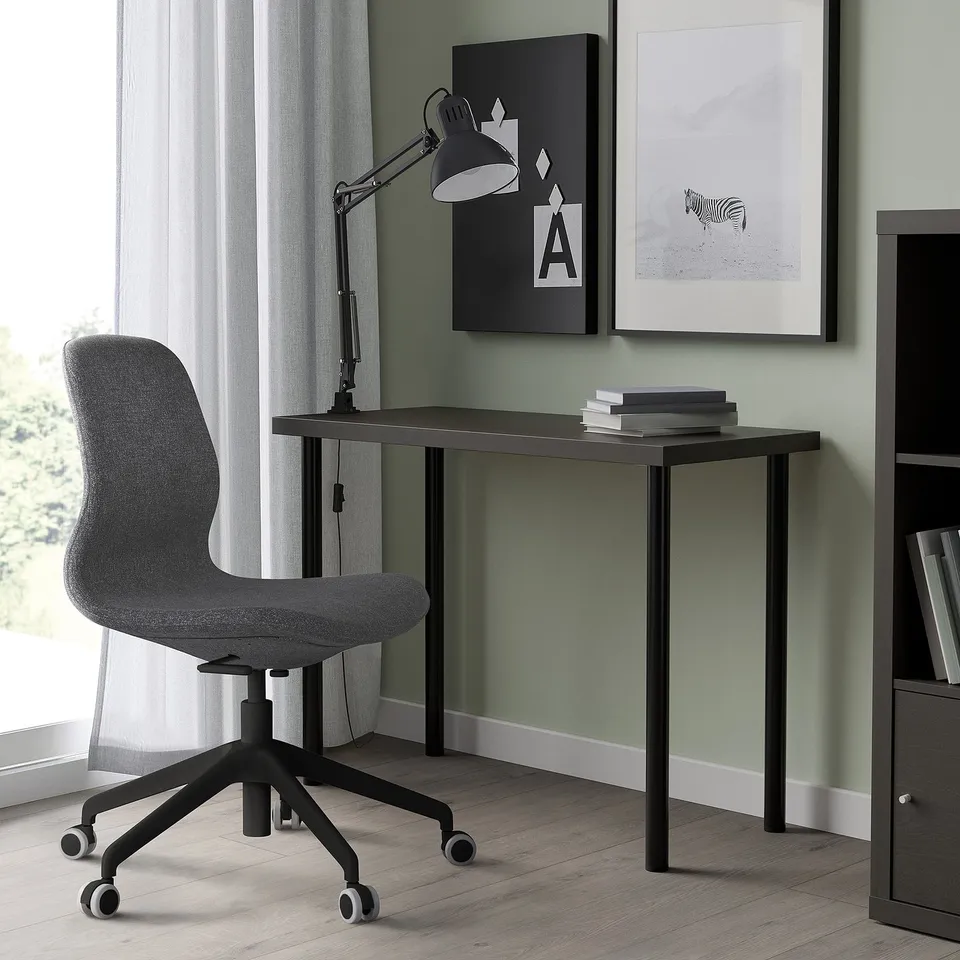 Modern home office setup with LINNMON desk, grey chair, adjustable lamp, and wall art. Desk shallow, fits small spaces.