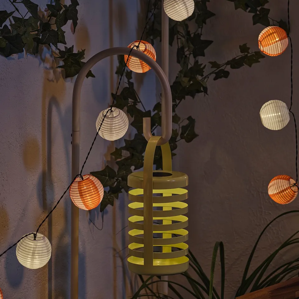 A decorative SOLVINDEN outdoor light with multiple lanterns, powered by solar energy, shedding warm light at night.
