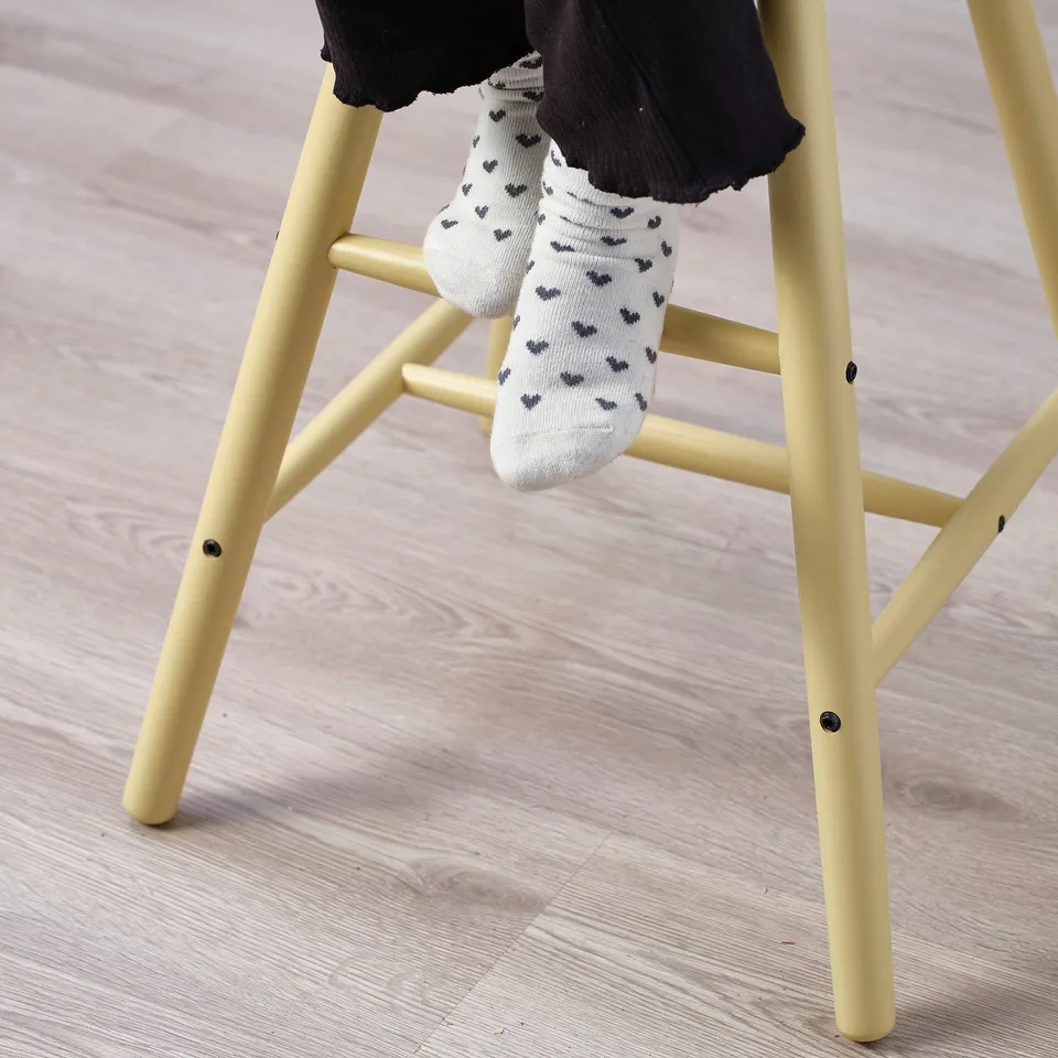 Childs yellow step stool. White socks with hearts on someones feet.
