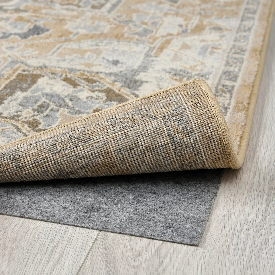 Close-up of a rolled, stylish area rug with neutral colours and intricate patterns.