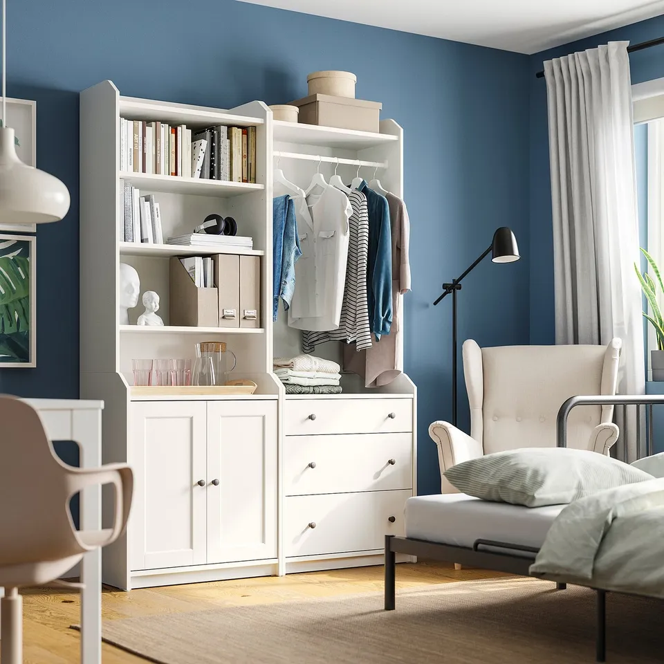 HAUGA storage unit with clothes, books, drawers, and chair with pillow.