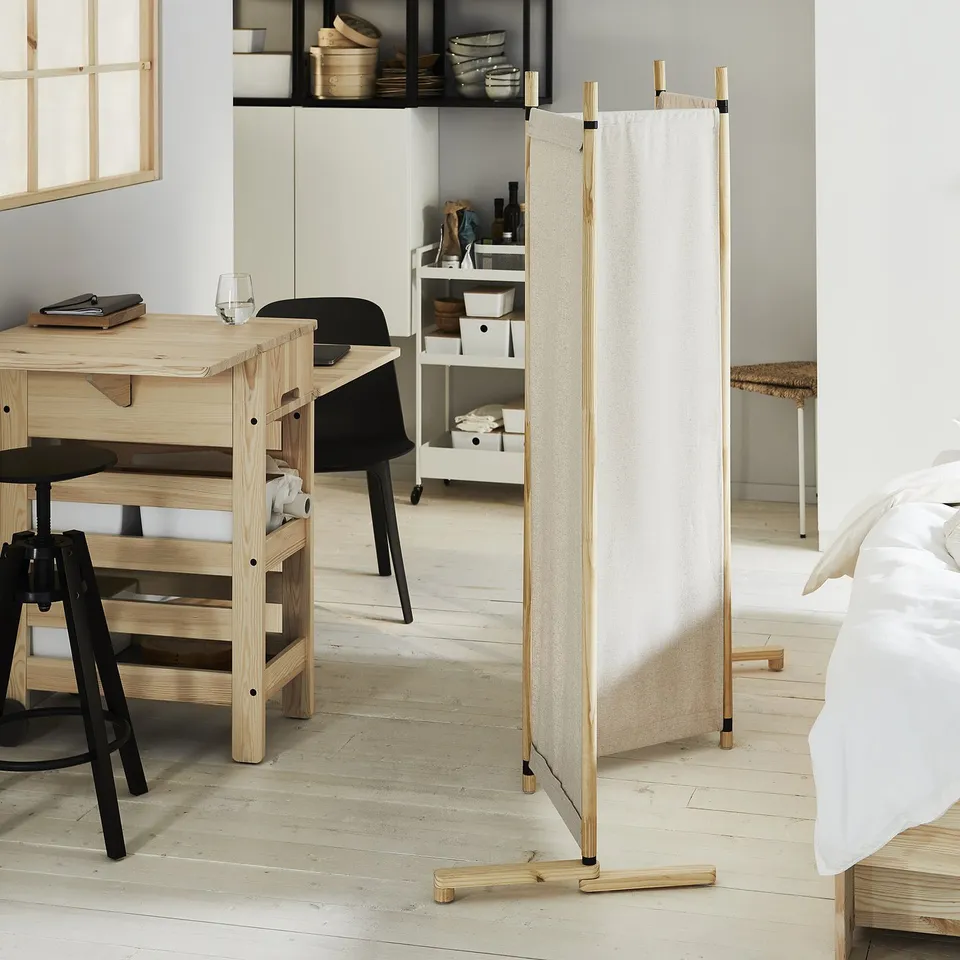 Modern, light wood room divider with beige fabric panels splits living space.