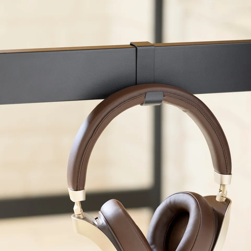 Over-the-ear headphones hang on desk stand.