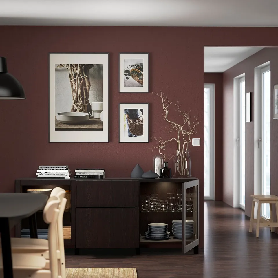 Modern sideboard with adjustable shelves, displaying dinnerware, vases, and decorations. Three framed artworks hang above.