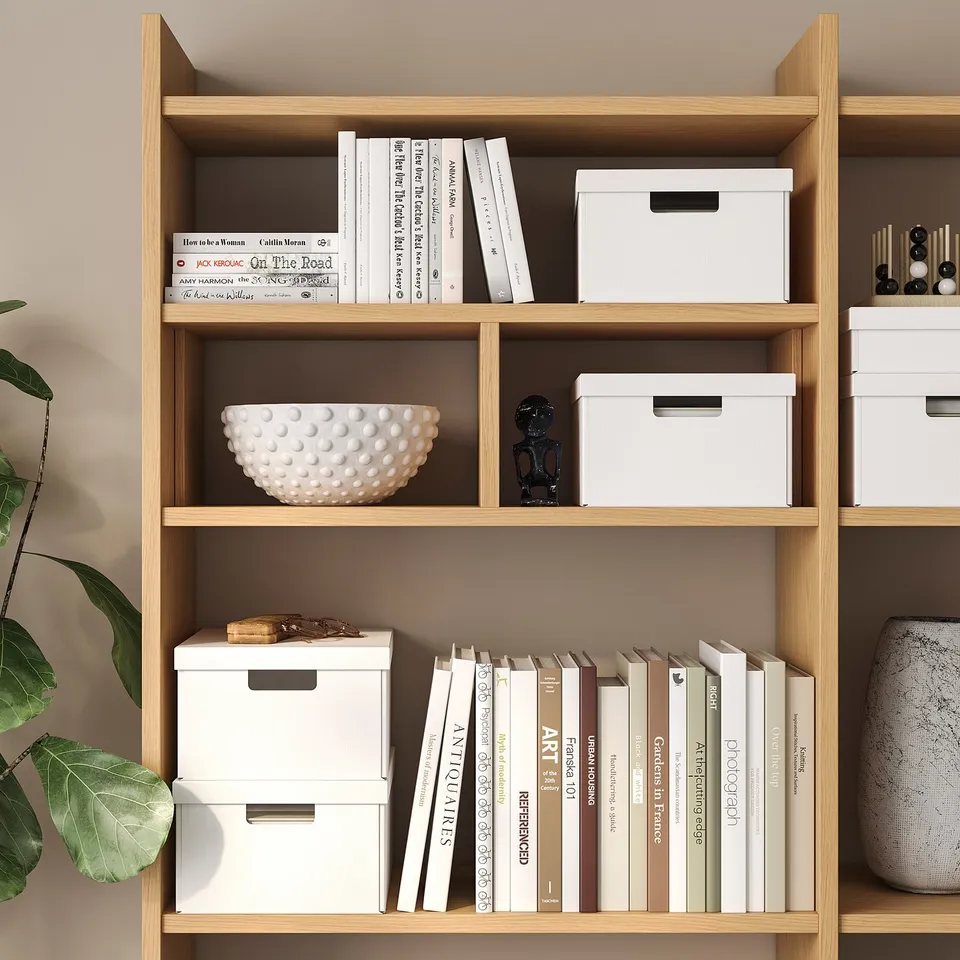 Bookshelf with white boxes for paper storage, books, and decorative items.