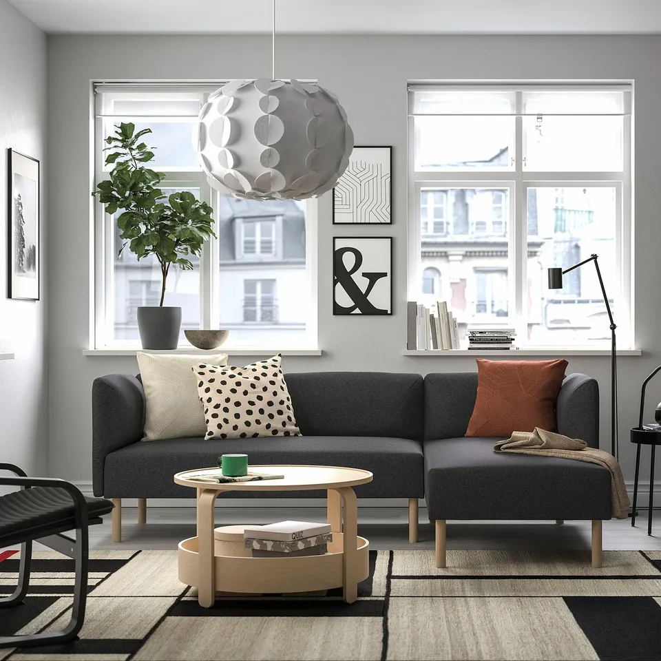 Modern living room featuring LILLEHEM modular grey sofa, wooden coffee table, patterned rug, large window, unique pendant light, and cosy pillows.