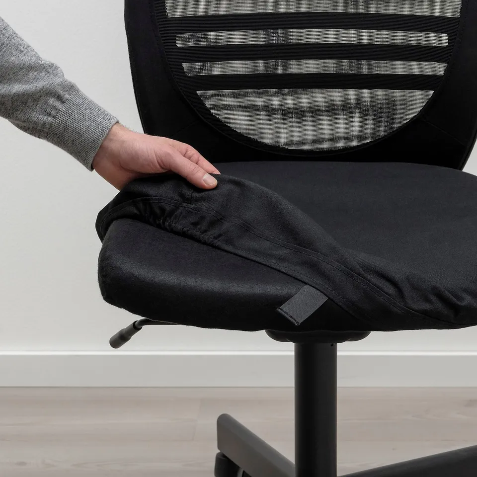 A person adjusting a FLINTAN office chair, demonstrating its removable, washable seat cover for easy cleaning.