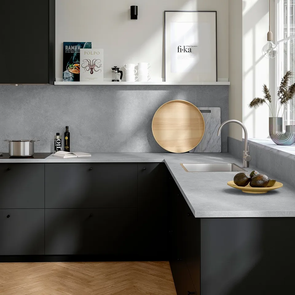 Modern kitchen with EKBACKEN grey worktop. A round wooden tray, avocados, cookbooks, and a sleek tap.