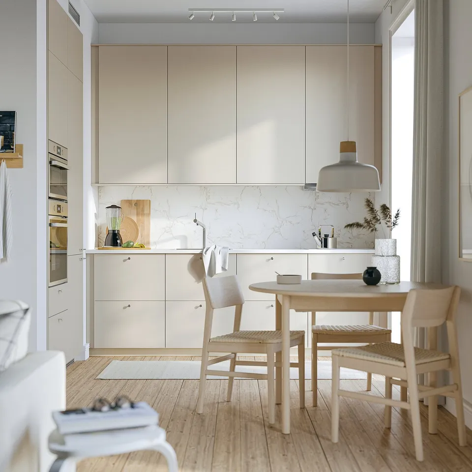 Modern kitchen: beige cabinets, marble backsplash, dining set under pendant light, white appliances, big window.