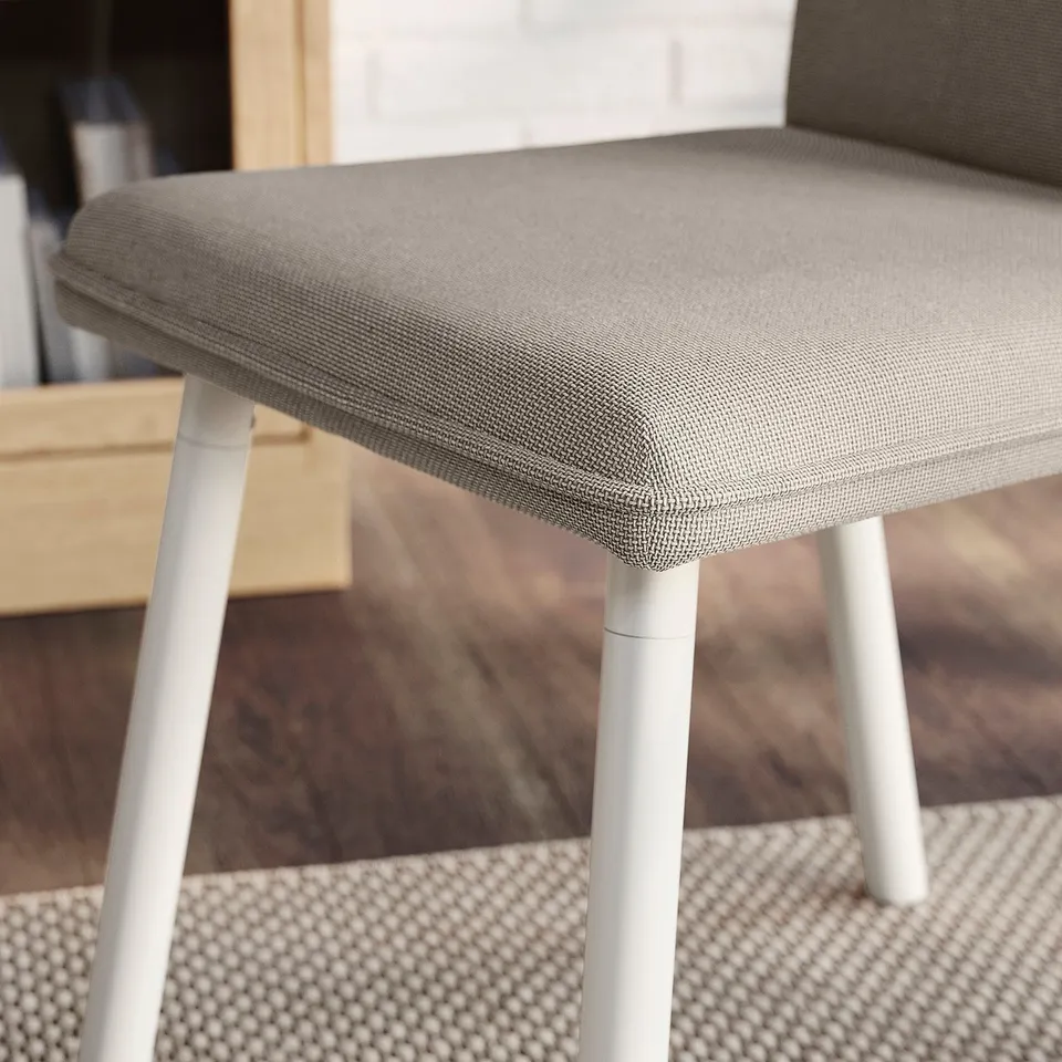 Close-up of modern chair, soft grey fabric, clean lines, sturdy white legs. Comfortable, durable design.