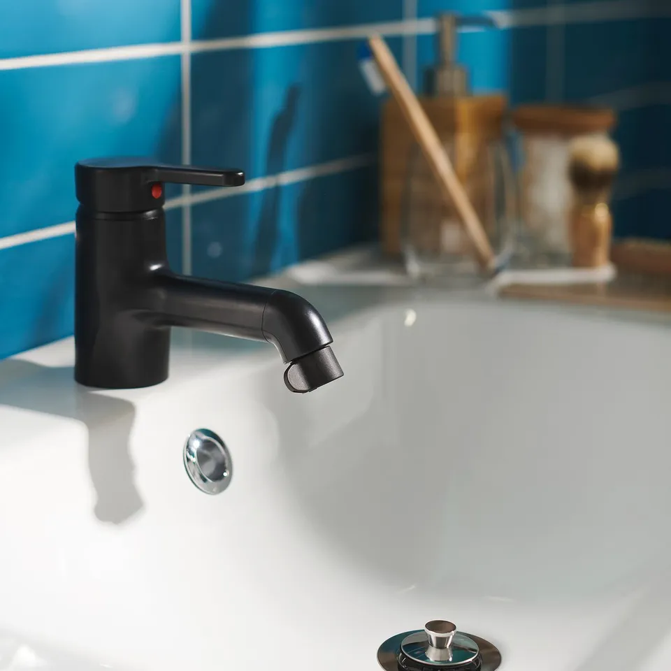 Black modern sink tap with sleek handle; clean white basin backdrop.