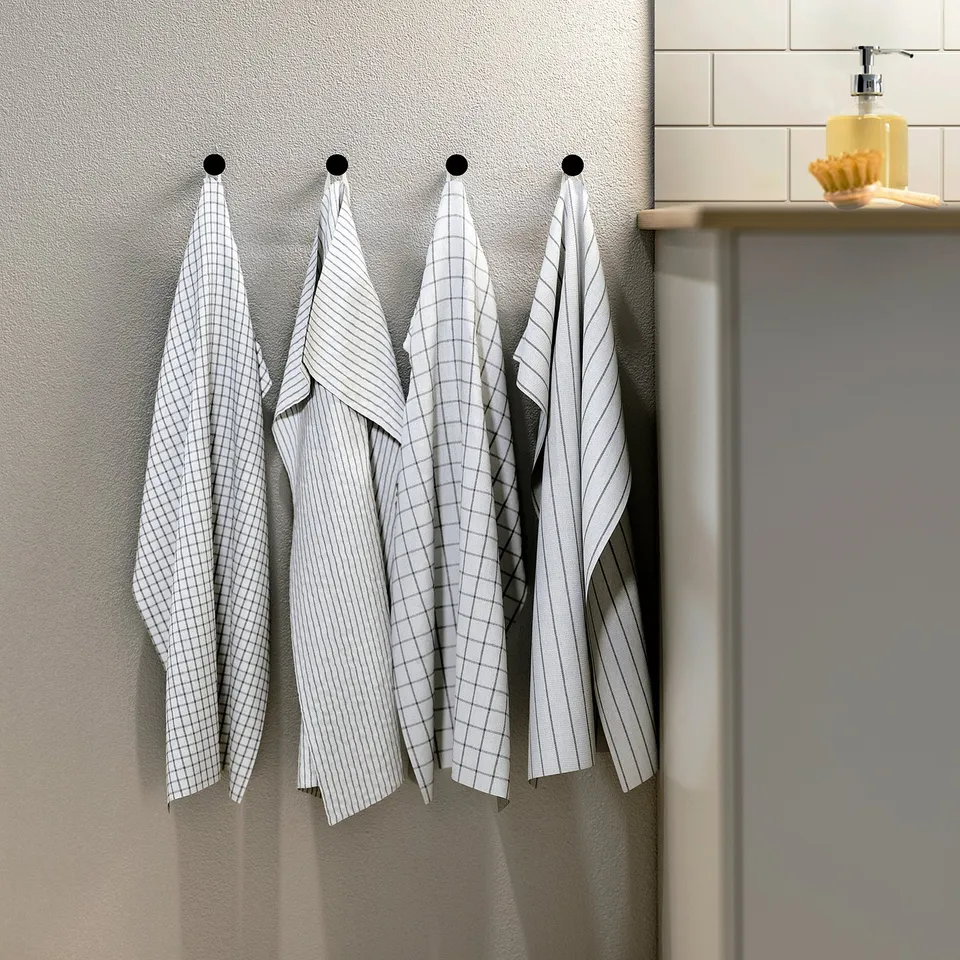 Four hanging white towels, each with different patterns, ready for kitchen use.