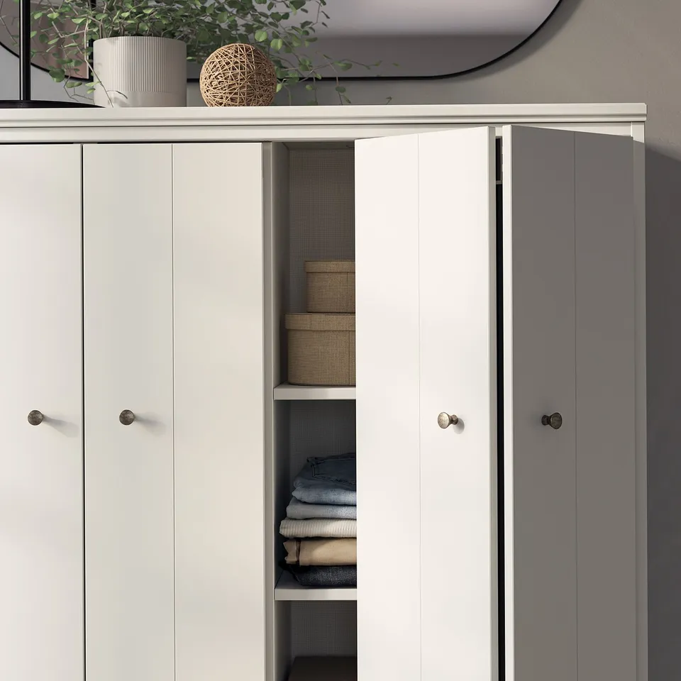 White IDANÄS wardrobe with open doors reveals neatly folded clothes in a well-organized interior.