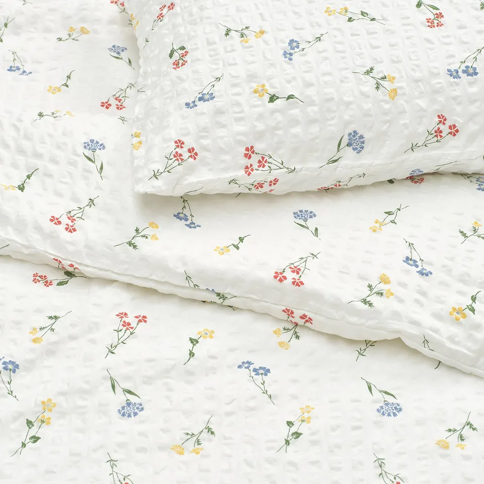 White duvet set with subtle floral designs and textured weave, laying smoothly.