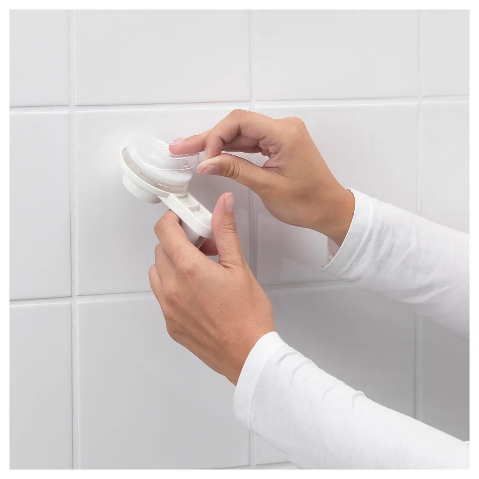 Person attaching white TISKEN white suction cup holder to tiled wall.