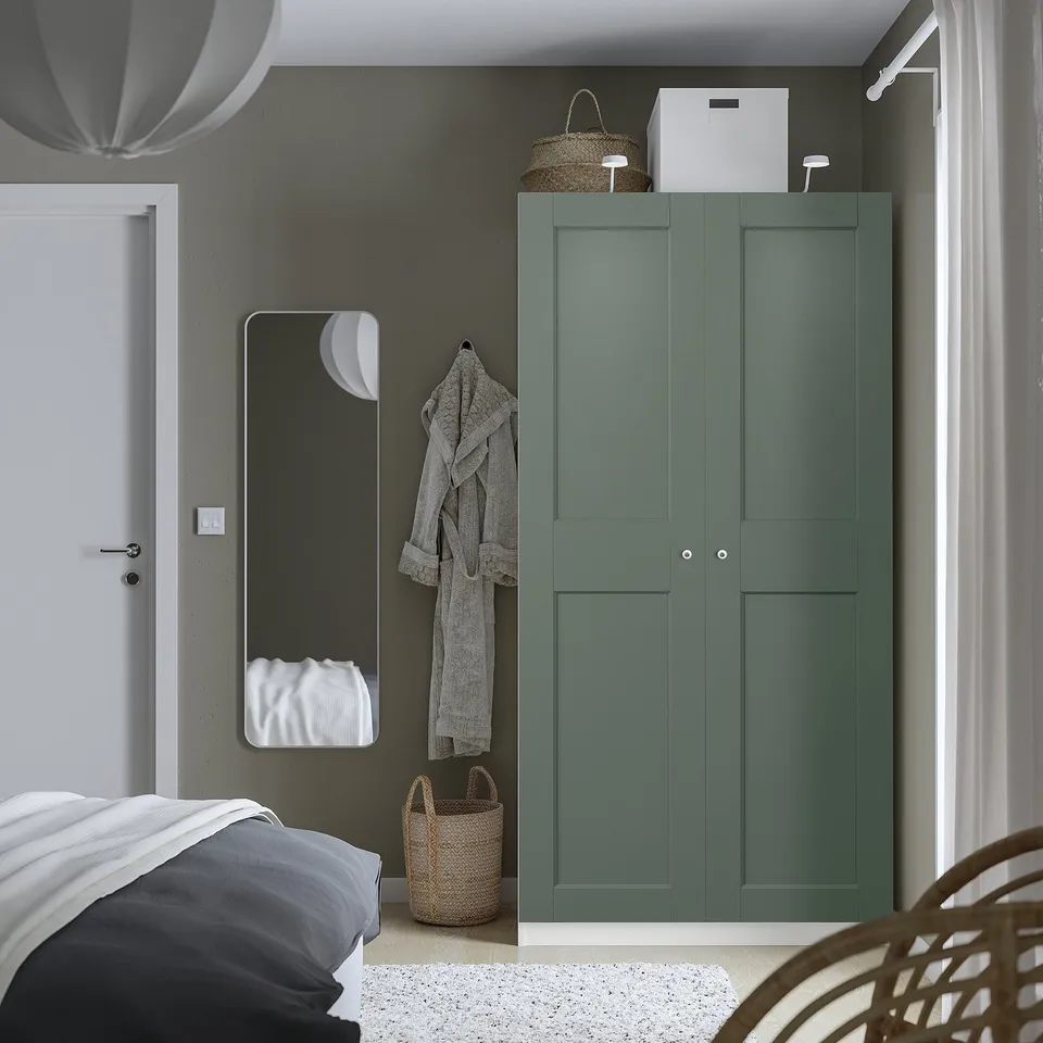 Minimalist bedroom with teal PAX wardrobe, grey linens, wicker basket, hanging robes, soft close doors.