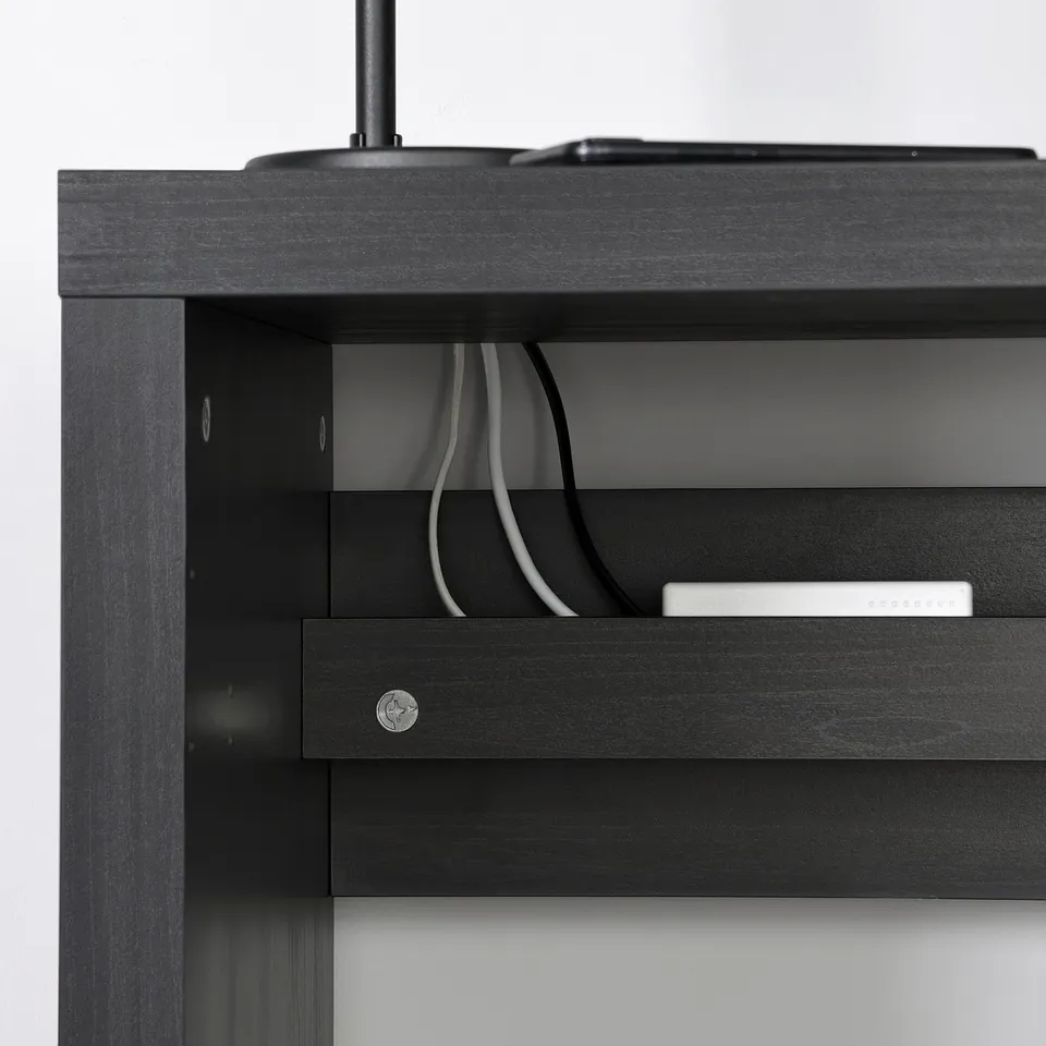 Black KALLAX shelf with cables routed through a cutout, showing organised wire management.