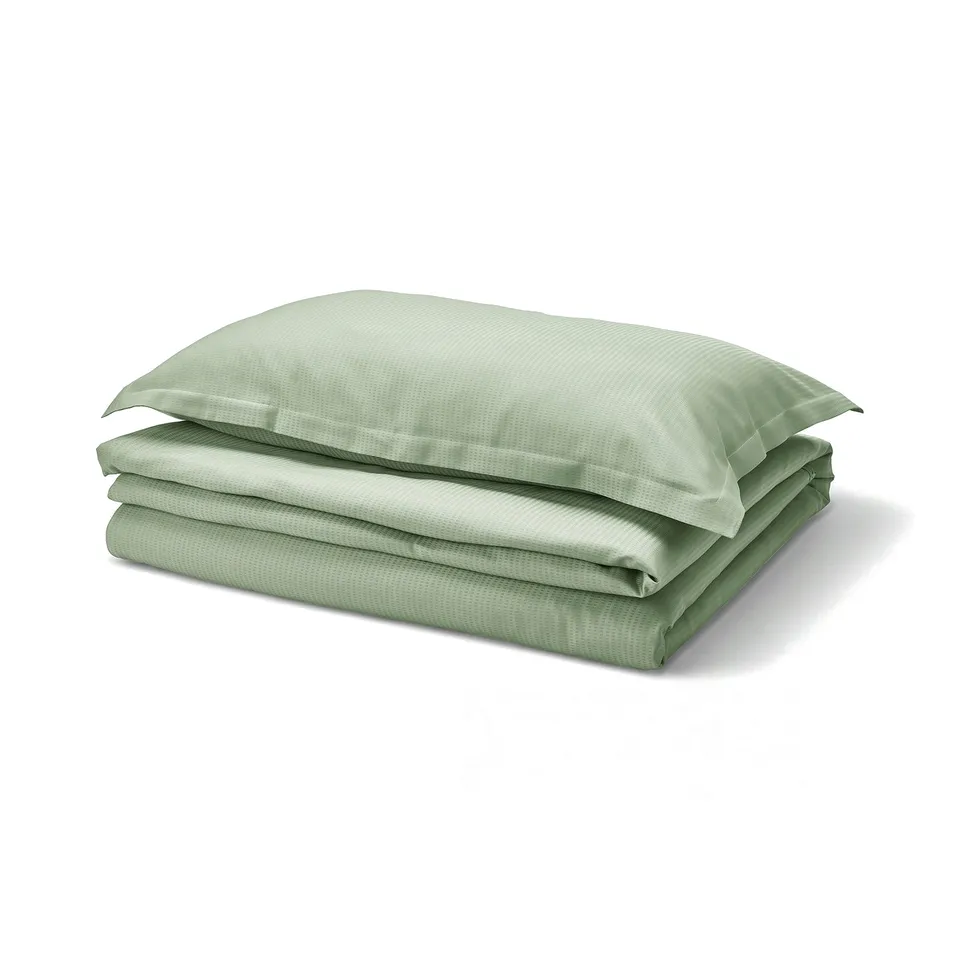 Green LÄKEVÄNDEROT bedding set, featuring a smooth, textured duvet and pillowcases with flange, neatly folded.