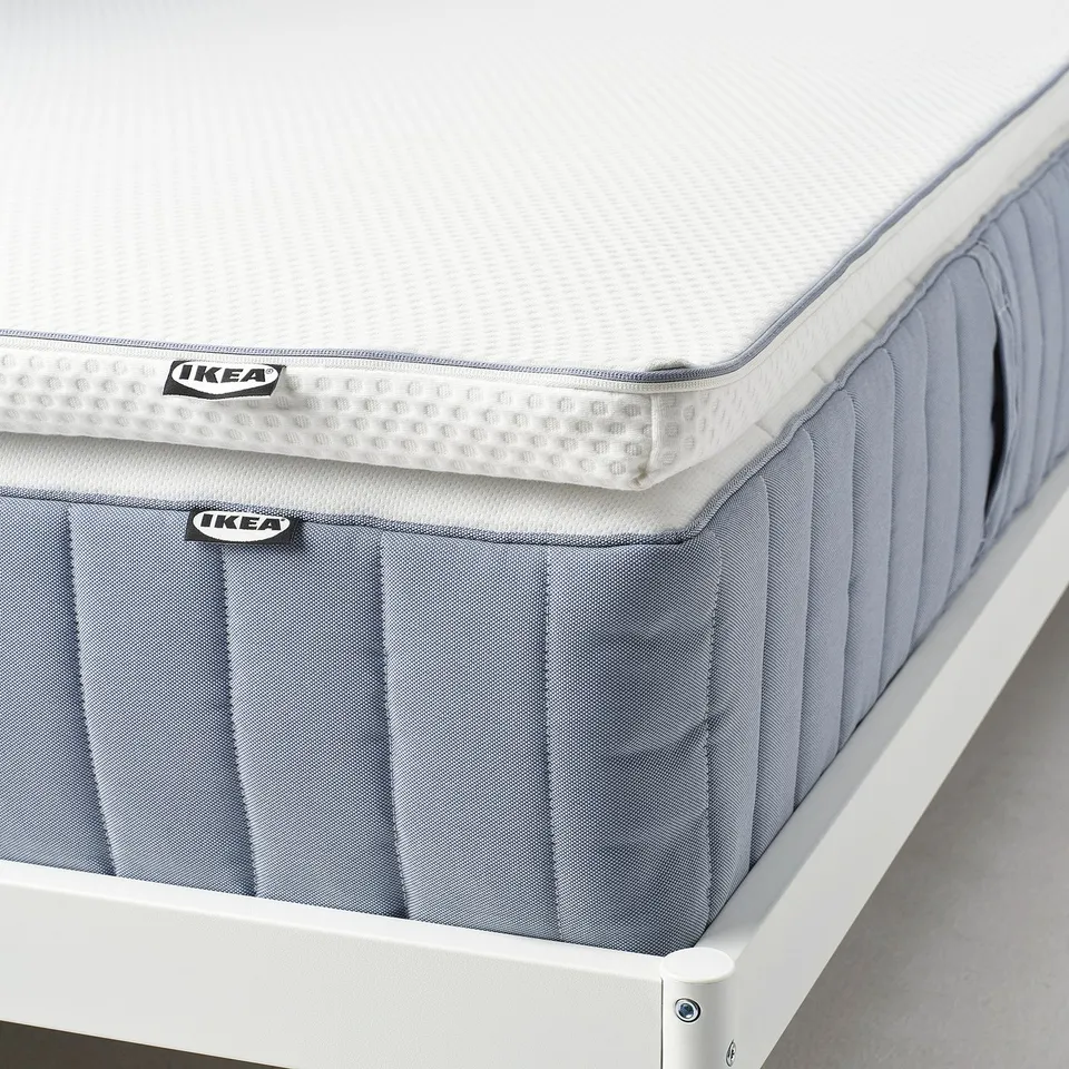 IKEA NÄSTABERG mattress pad with cooling and memory foam sides, shown on a white bed frame, with memory foam visible.