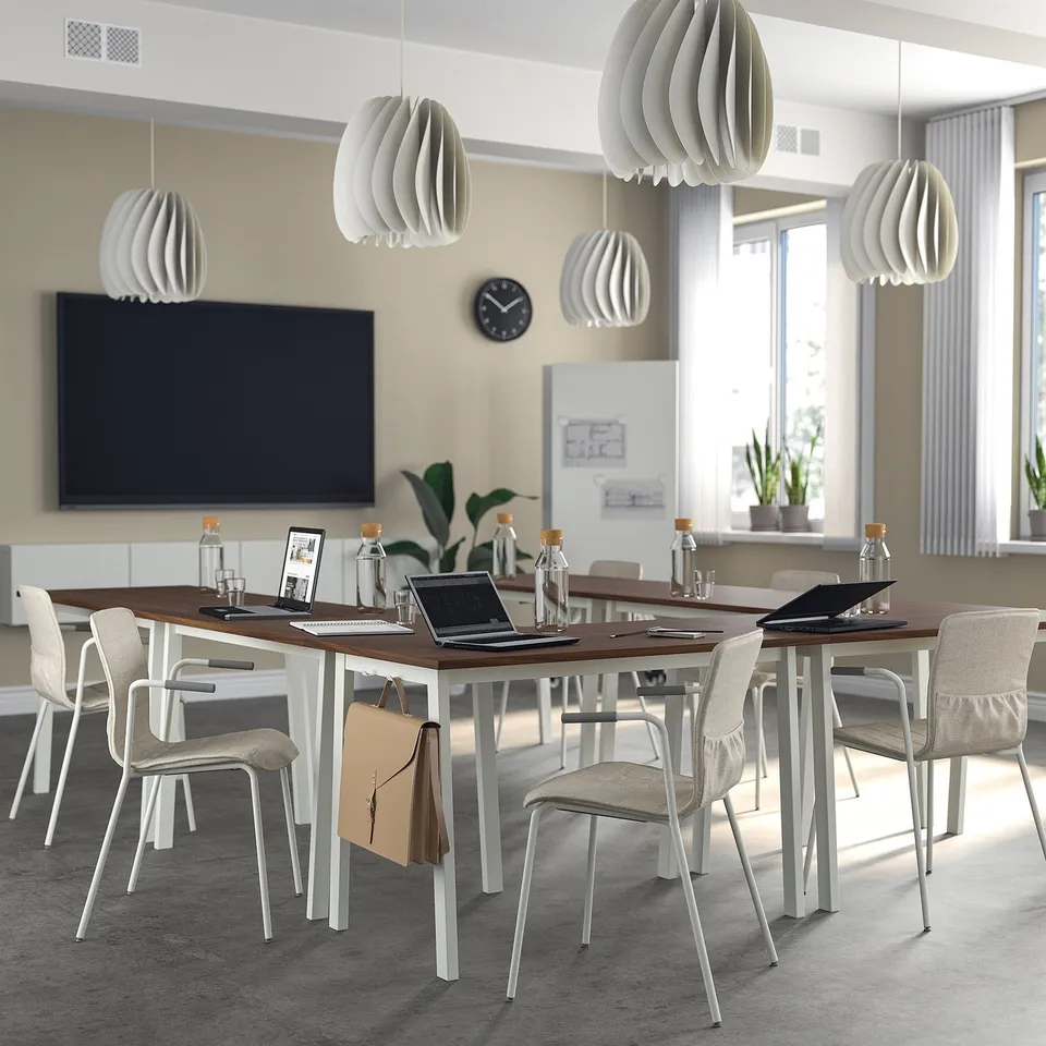 MITTZON conference table with pendant lights, laptops, and chairs. Wooden top, white legs, big screen, and natural light from windows.