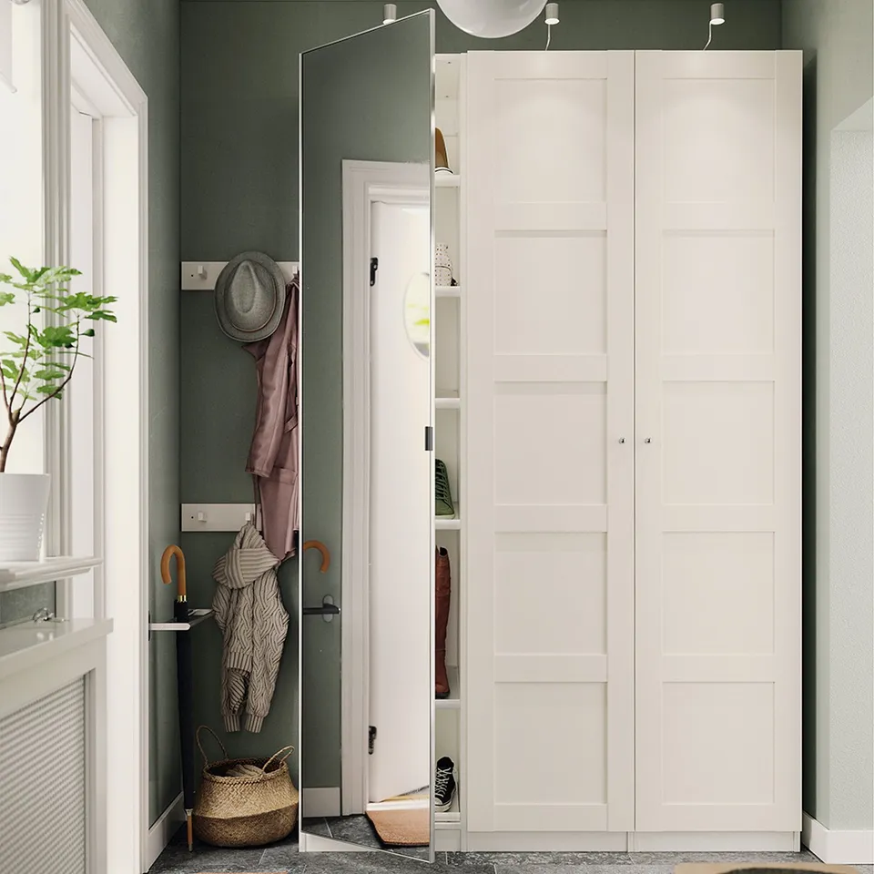 Depicts a narrow hallway with a white PAX wardrobe featuring mirror doors and an open closet showing stored items.
