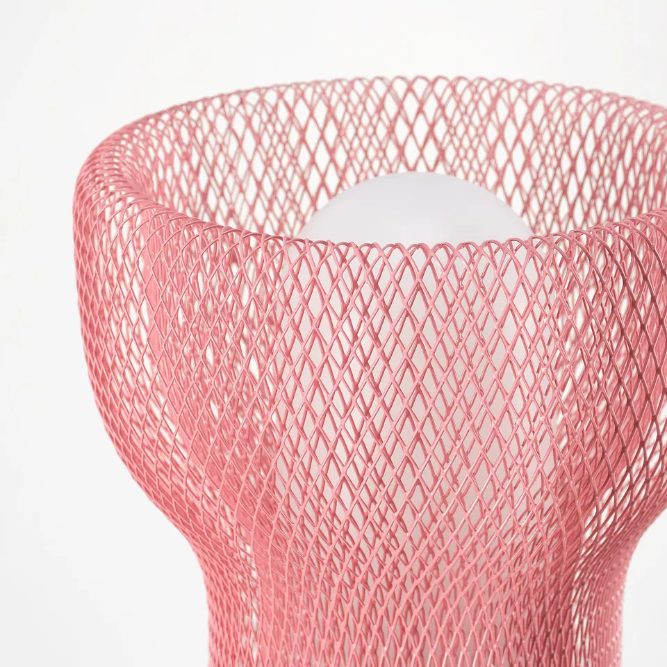 Close-up of a modern pink mesh lamp. Elegant design, intricate patterns, emitting soft light.