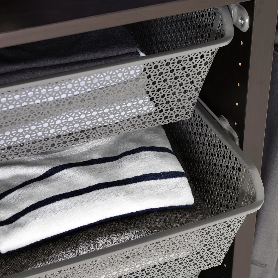 Metal wardrobe basket holds folded clothes, enhances air circulation.