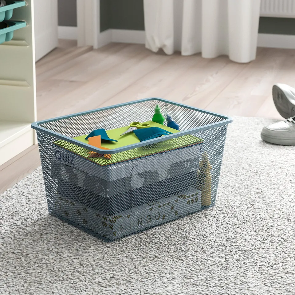 Mesh storage basket on carpet with colourful items. Part of TROFAST series for organising.