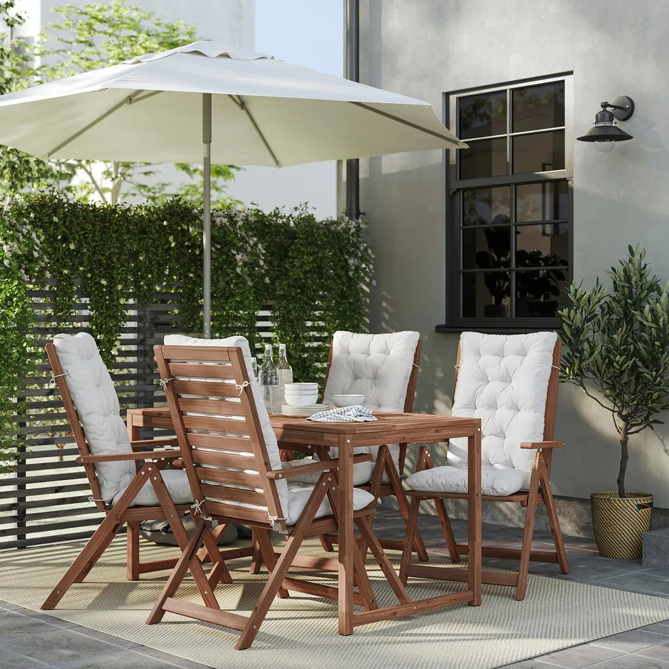 Cosy outdoor dining set with 4 chairs, a square table, and beige cushions under a white umbrella on a patio.