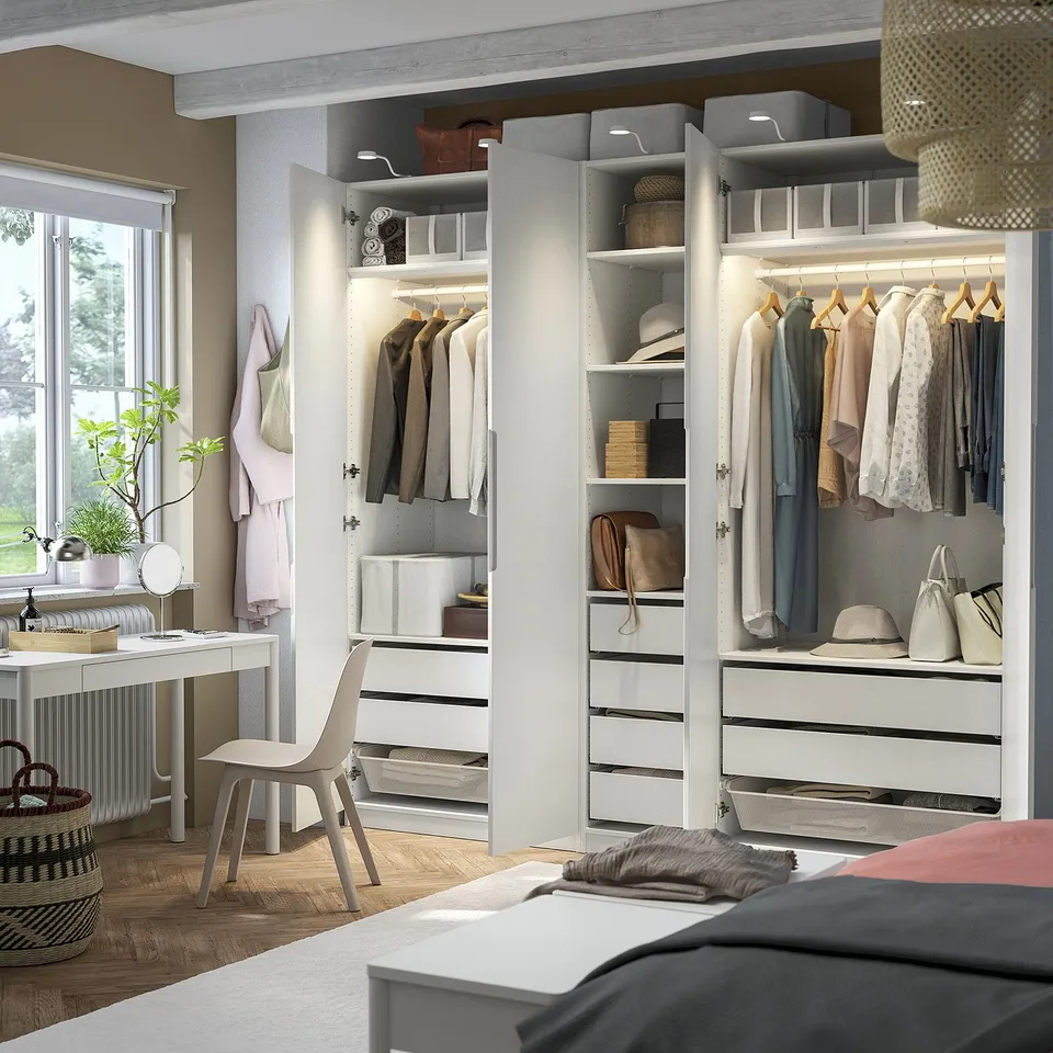 Modern bedroom with open wardrobe, organised clothes, and integrated lighting.