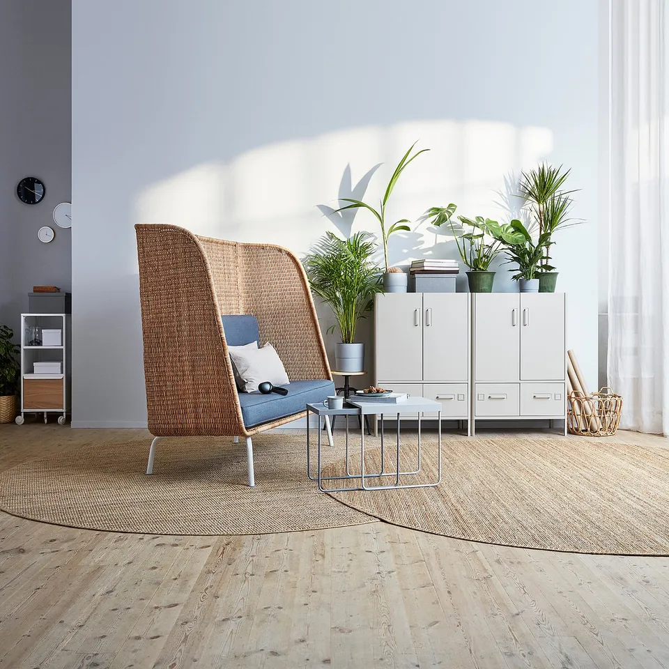 Modern office with IDÅSEN white cabinet, wicker chair, plants, and small table.