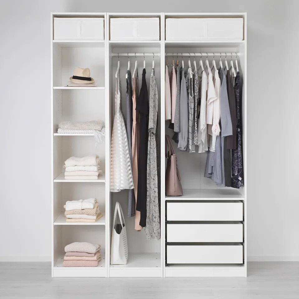 A minimalist wardrobe, PAX, featuring shelves with stacked clothes and hanging garments, drawers, and adjustable feet for floor compensation.
