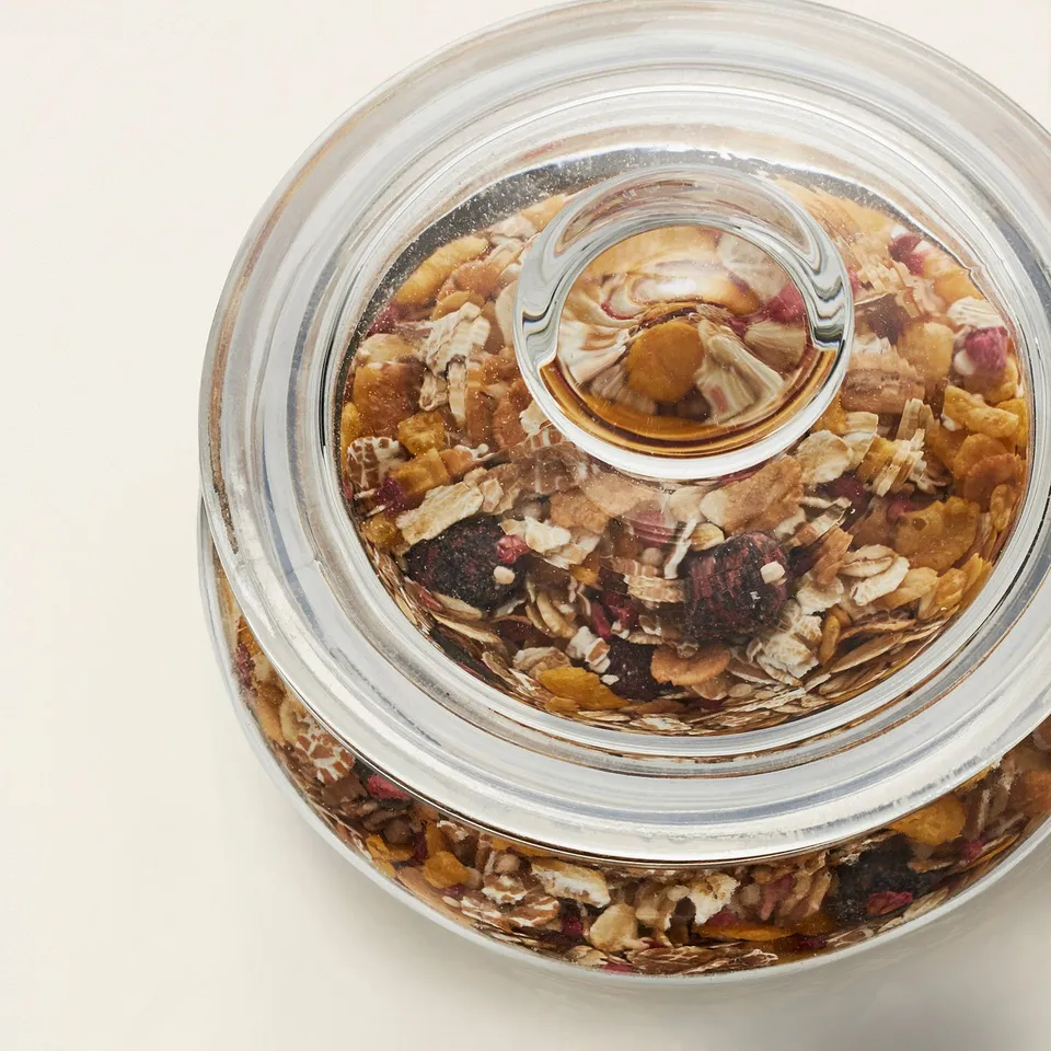 Clear glass jar with removable lid displays colourful granola mix.