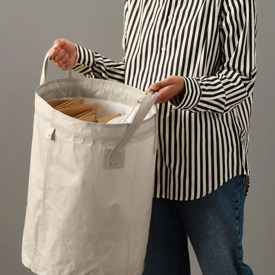 Person holding a large, foldable DIMPA bag with multiple compartments, ideal for sorting laundry or waste.