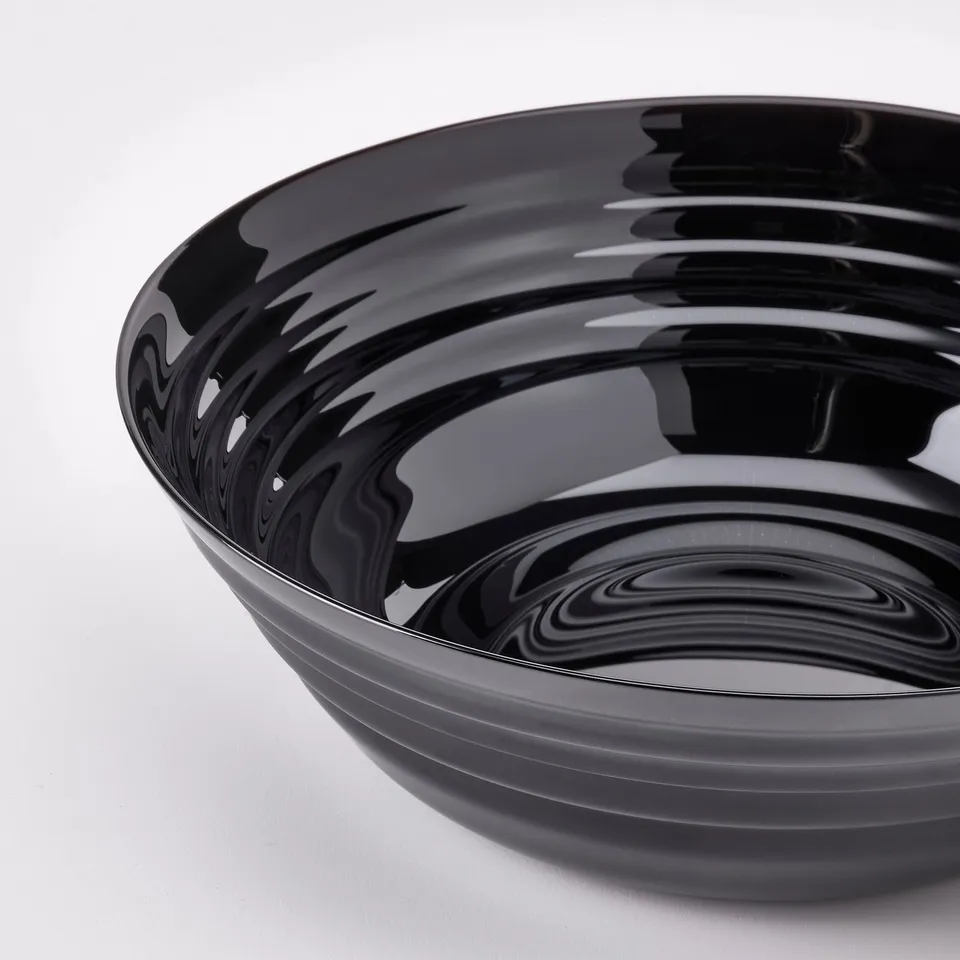 Black glossy bowl with a swirling pattern, reflecting light. Shiny surface, elegant design.