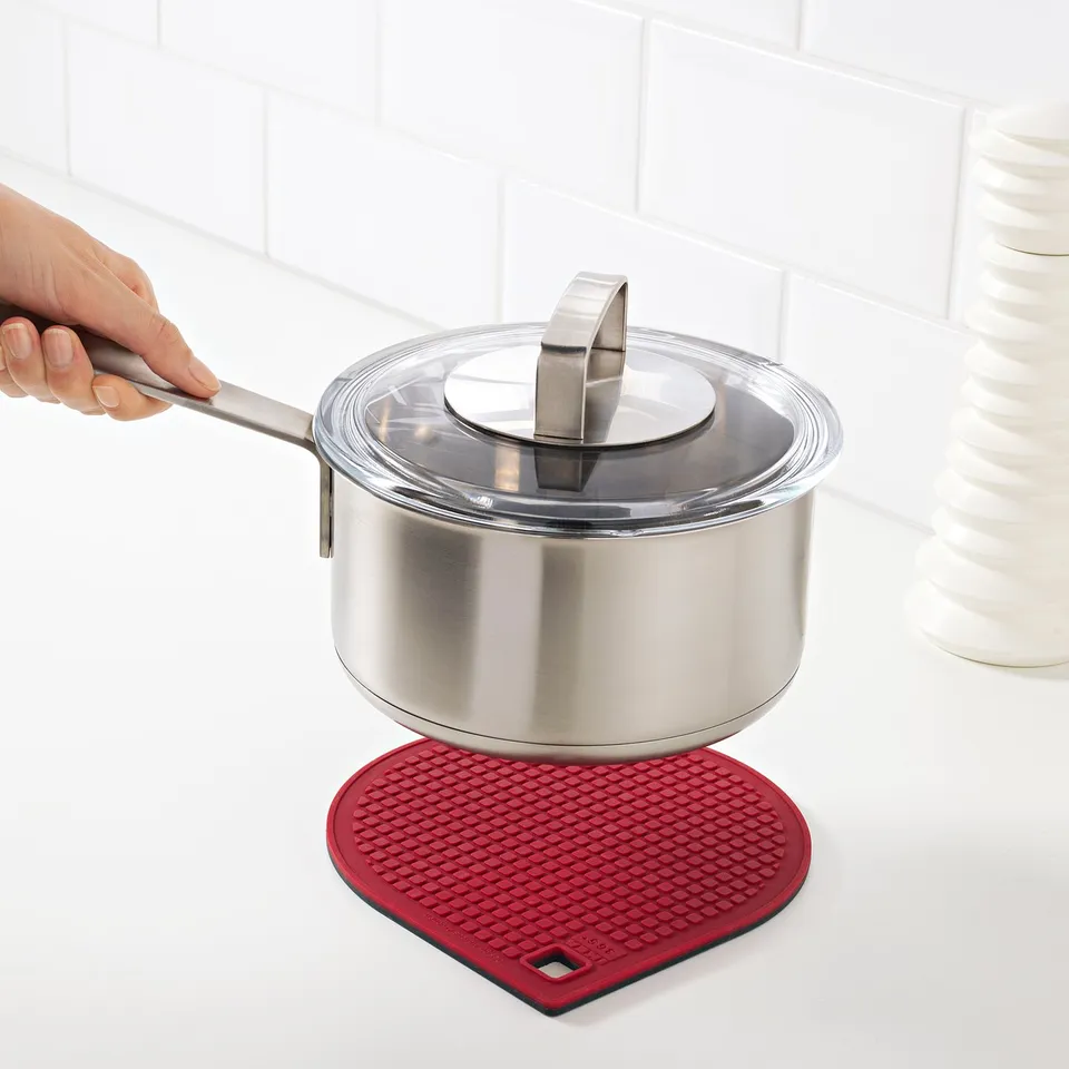 Hand holds pots handle on magnetic stand, red silicone base.