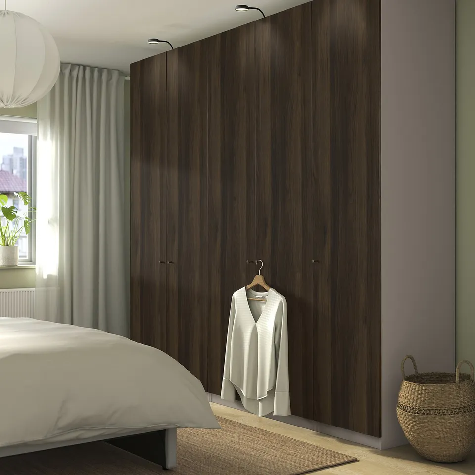 Minimalist bedroom with tall dark brown PAX wardrobe, ample storage.