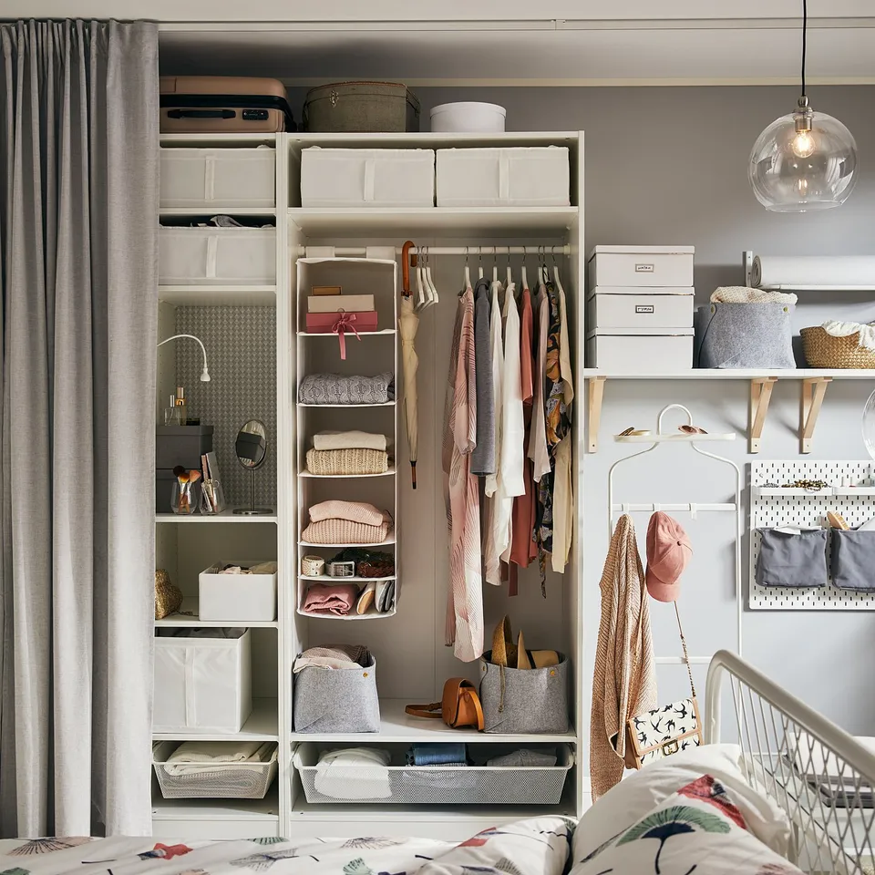 Bedroom with white PAX wardrobe, shelves, clothes, and accessories.