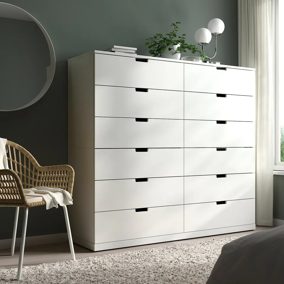 Modern NORDLI 6-drawer chest in room corner, with mirror and chair.
